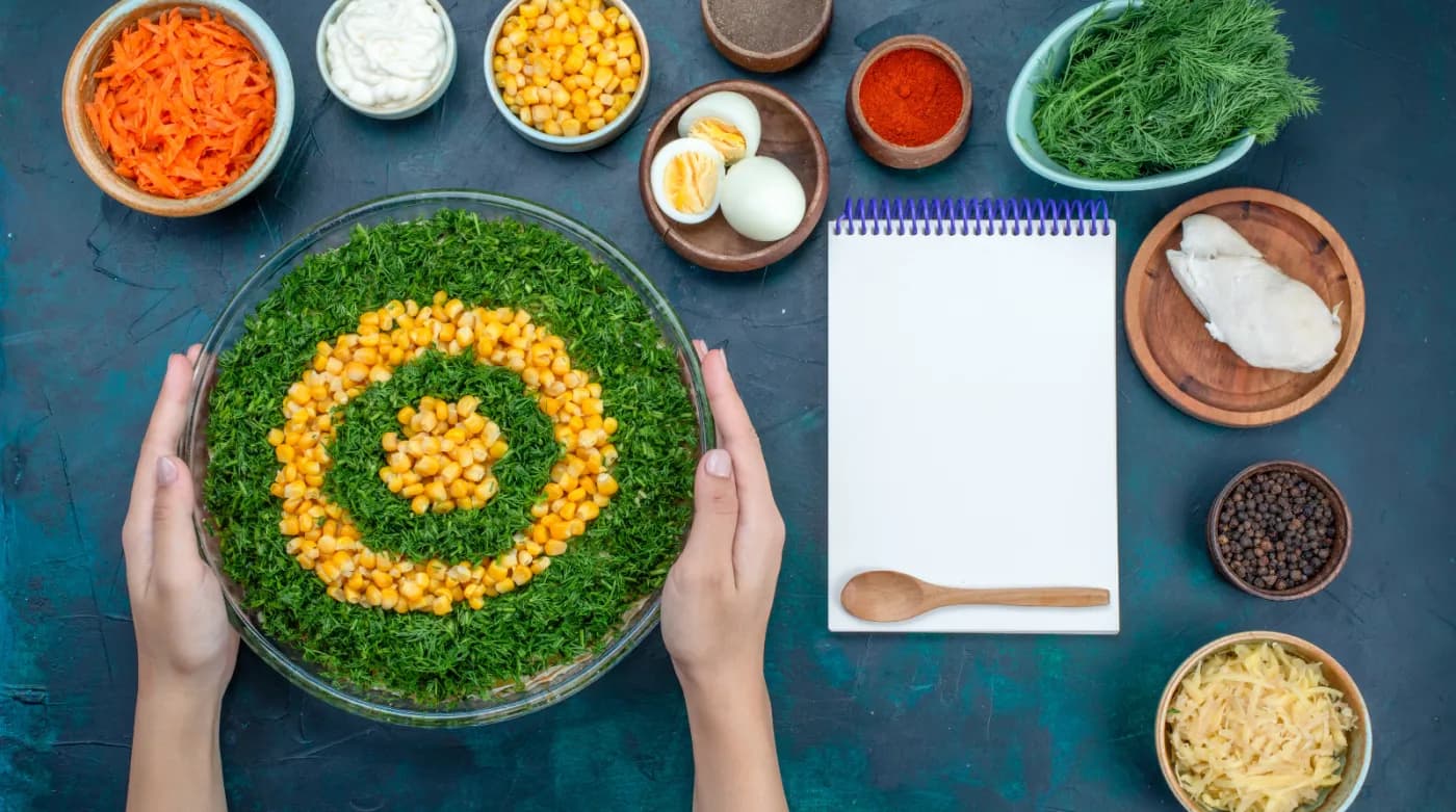 Hands arranging fresh ingredients beside an open notebook